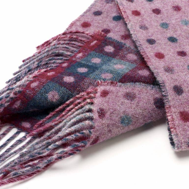 Folded pink scarf with polka dot pattern on a white background