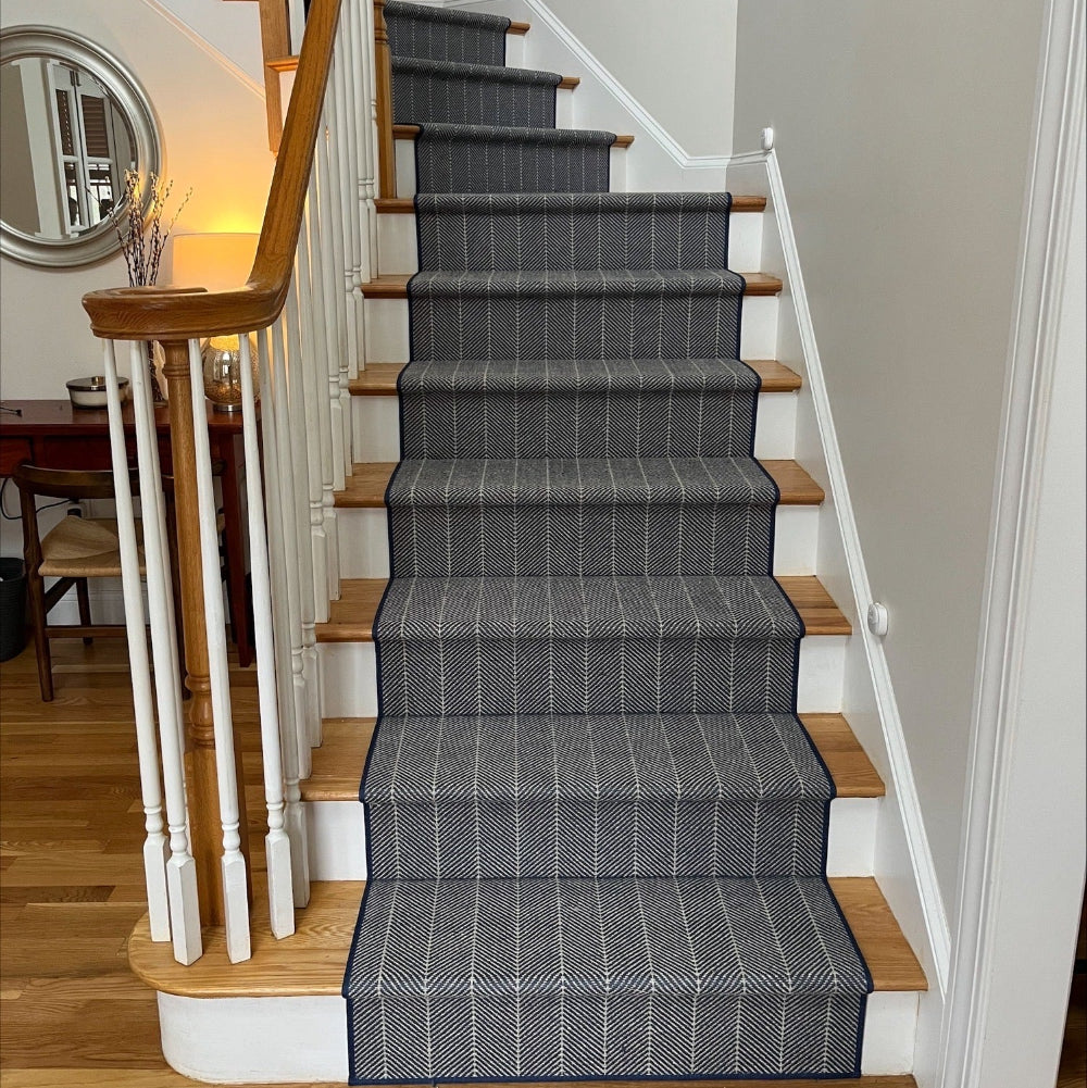Staircase with gray striped carpet and wooden steps in a home setting.