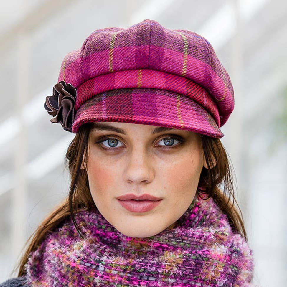 Woman wearing a pink plaid hat and matching scarf with a blurred background