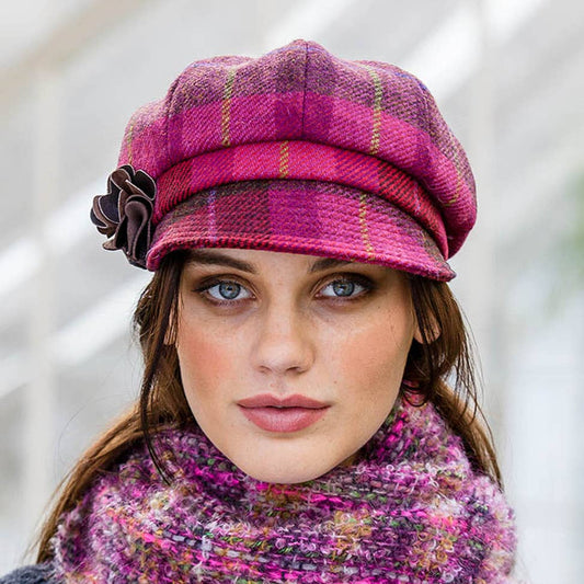 Woman wearing a pink plaid hat and matching scarf with a blurred background