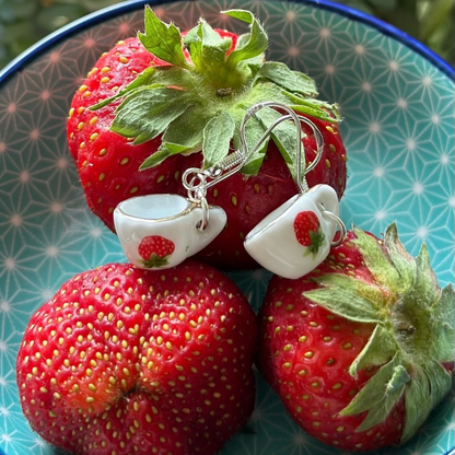Teacup-shaped earrings on strawberries with a patterned background
